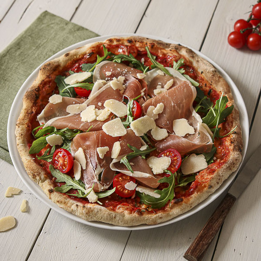 Sauce tomate, fromage italien rapé. Après cuisson : roquette, tomates cerises, prosciutto crudo, copeaux de fromage italien