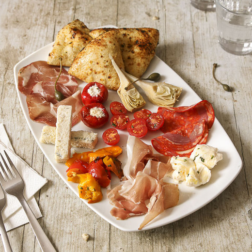 Grand assortiment d’antipasti : charcuteries et fromages italiens, légumes et pains Del Arte