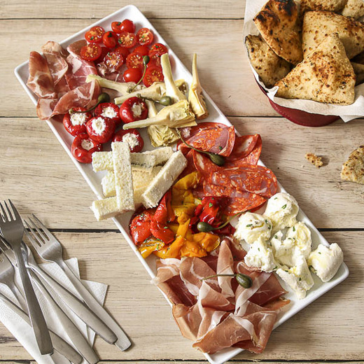 Grand assortiment d’antipasti : charcuteries et fromages italiens, légumes et pains Del Arte