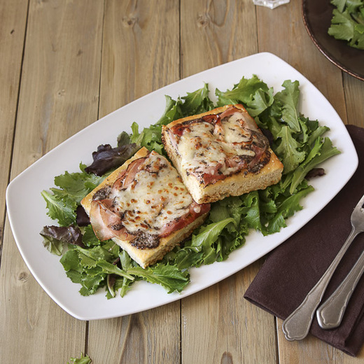 Pain focaccia, crème et sauce champignons à la truffe d'été (Tuber aestivum), jambon aux herbes, gratiné à la mozzarella . Servi avec salade.