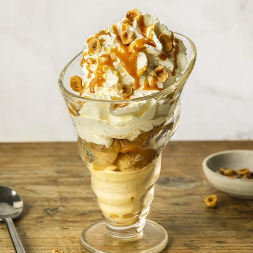 Crèmes glacées vanille de Madagascar et caramel au beurre salé, quartiers de pommes rôties, crème fouettée, lait caramélisé, noisettes d'Italie Crèmes glacées vanille de Madagascar et caramel au beurre salé, quartiers de pommes rôties, crème fouettée, lait caramélisé, noisettes d'Italie