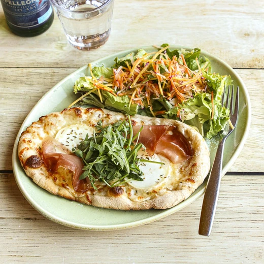Notre Chèvre et miel en format pizzetta, accompagnée d'une salade Notre Chèvre et miel en format pizzetta, accompagnée d'une salade